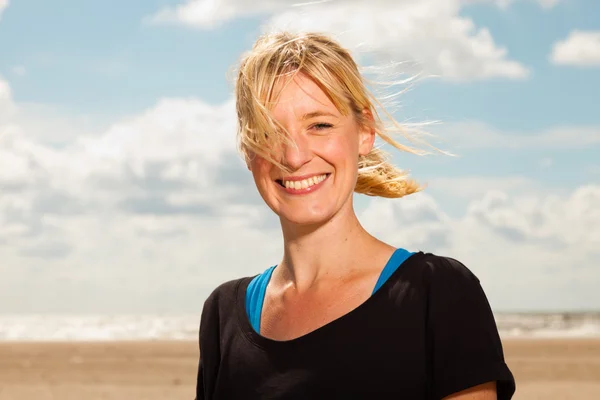 Feliz mujer rubia bonita en la playa. Disfrutando de la naturaleza. Cielo nublado azul. Usar suéter negro . —  Fotos de Stock