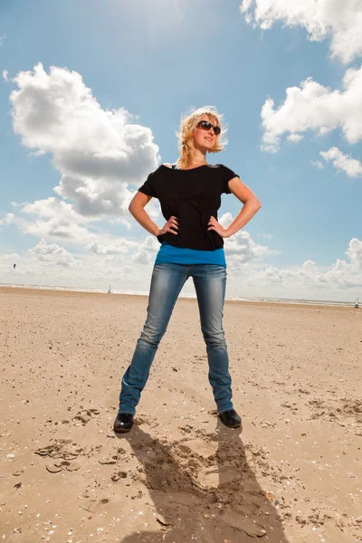 Glückliche hübsche blonde Frau am Strand. Natur genießen. blauer bewölkter Himmel. trägt schwarzen Pullover und Sonnenbrille. — Stockfoto