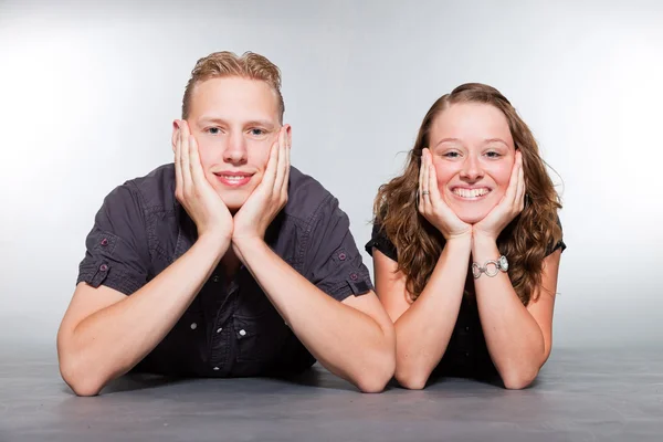 Happy young couple casual dressed. Studio shot isolated on grey background. Man with short blond hair. Woman long brown hair. — Stock Photo, Image