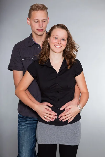 Happy young couple casual dressed. Studio shot isolated on grey background. Man with short blond hair. Woman long brown hair. — Stock Photo, Image