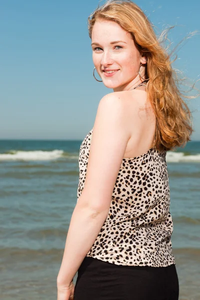 Ευτυχισμένο το όμορφο κορίτσι με μακριά κόκκινα μαλλιά, απολαμβάνοντας δροσιστικά παραλία την ημέρα καλοκαίρια. σαφή μπλε ουρανό. — Φωτογραφία Αρχείου