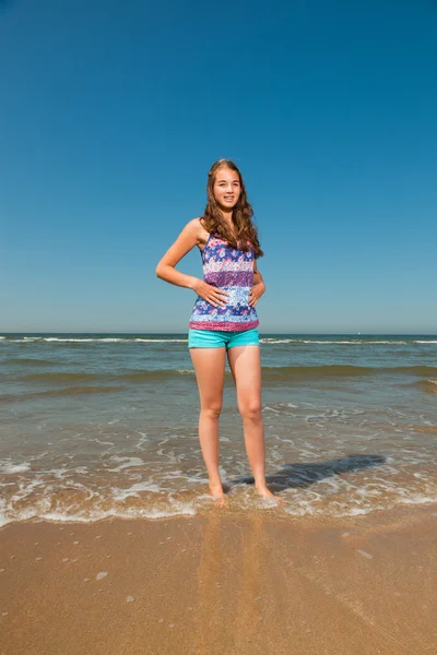 Jolie jolie fille aux longs cheveux bruns profitant de la plage rafraîchissante lors d'une chaude journée d'été. Ciel bleu clair . — Photo