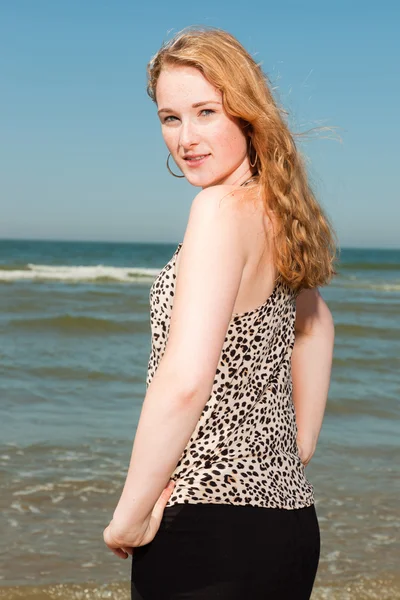 Menina bonita feliz com cabelos longos vermelhos apreciando a praia refrescante no dia de verão quente. Céu azul claro . — Fotografia de Stock