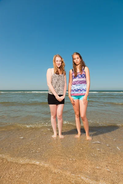 Två vackra flickor spela och njuta av den uppfriskande på en varm sommardag. klar blå himmel. att ha kul på stranden. — Stockfoto