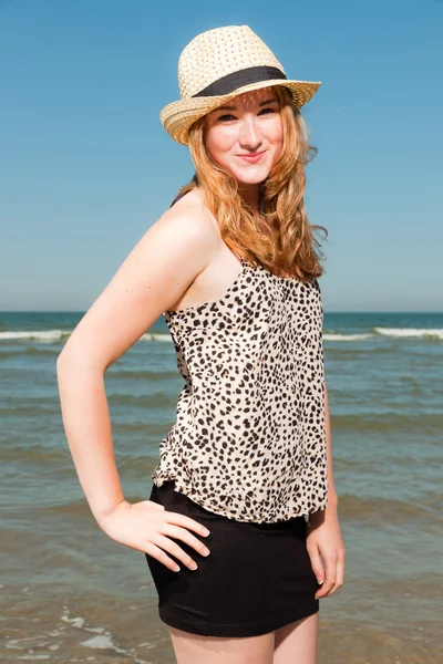Uzun kızıl saçlı ve ferahlatıcı sahilde sıcak yaz gününde zevk şapka mutlu güzel kız. Açık mavi gökyüzü. — Stok fotoğraf