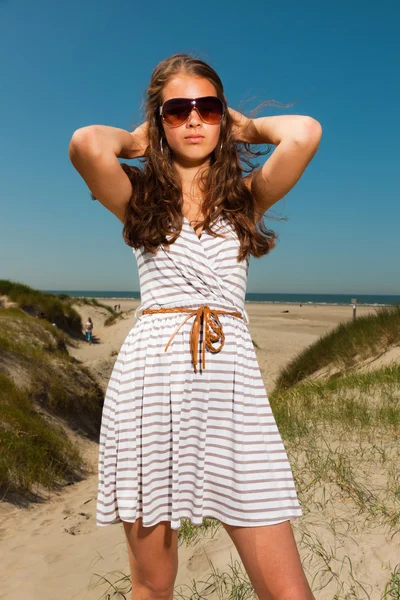 긴 갈색 머리 뜨거운 여름 날에 해변 근처 모래 언덕을 즐기는 행복 한 예쁜 여자. singlasses 입고. 푸른 하늘을 취소. — 스톡 사진