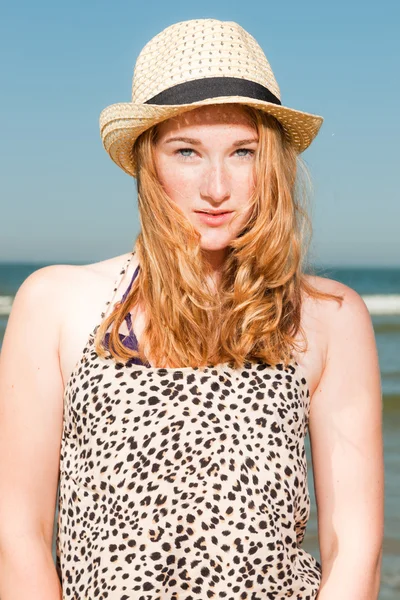 Gelukkig mooi meisje met lang rood haar en hoed genieten van de verfrissende strand op hete zomers dag. duidelijke blauwe hemel. — Stockfoto