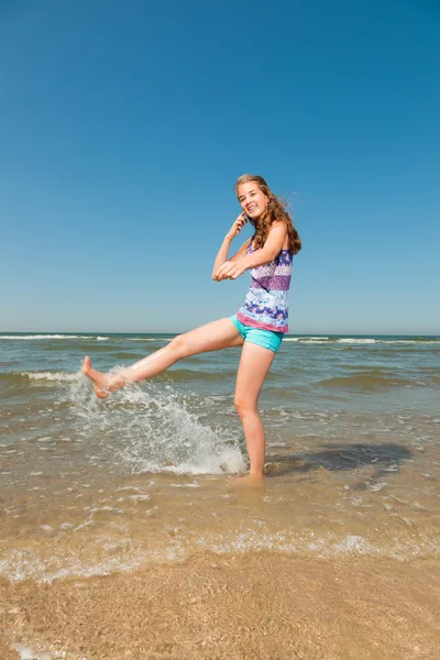 Glad söt flicka med långa bruna hår njuta av uppfriskande stranden på varm sommardag. klar blå himmel. — Stockfoto