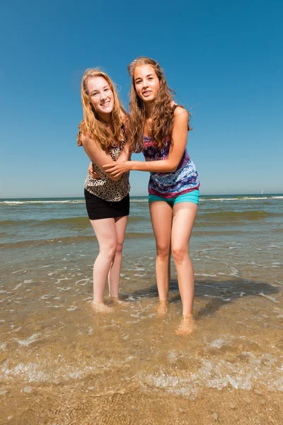 Duas garotas bonitas brincando e desfrutando do refrescante em um dia quente de verão. Céu azul claro. Divertindo-se na praia . — Fotografia de Stock