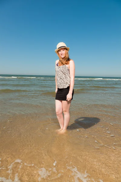 Šťastné hezká dívka s dlouhé červené vlasy a klobouk těší osvěžující pláž horká léta den. modré nebe nad hlavou. — Stock fotografie