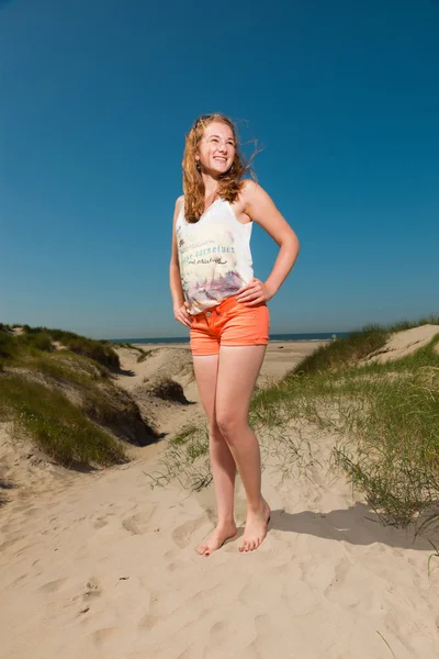 Feliz chica bonita con el pelo largo y rojo disfrutando de dunas de arena cerca de la playa en el día de los veranos calurosos. Cielo azul claro . —  Fotos de Stock