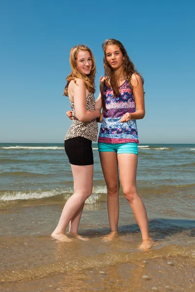 Due belle ragazze che giocano e si godono il rinfrescante in una calda giornata estiva. Cielo blu chiaro. Divertirsi in spiaggia . — Foto Stock