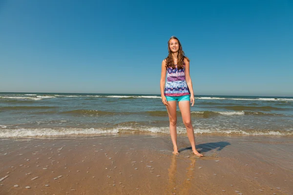 Feliz chica bonita con el pelo largo y castaño disfrutando de la refrescante playa en el caluroso día de verano. Cielo azul claro . —  Fotos de Stock