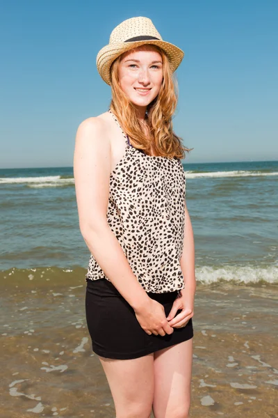 Felice bella ragazza con lunghi capelli rossi e cappello godendo la spiaggia rinfrescante nelle estati calde giorno. Cielo azzurro chiaro . — Foto Stock