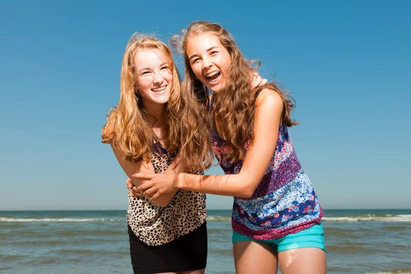 Twee mooie meisjes spelen en genieten van de verfrissende op een hete zomers dag. duidelijke blauwe hemel. plezier op het strand. — Stockfoto