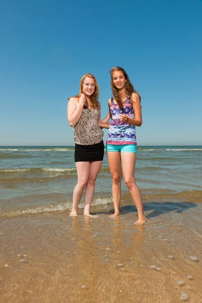 Twee mooie meisjes spelen en genieten van de verfrissende op een hete zomers dag. duidelijke blauwe hemel. plezier op het strand. — Stockfoto