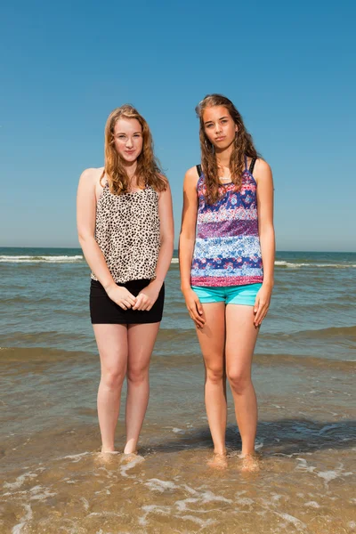 Dos chicas guapas jugando y disfrutando de lo refrescante en un caluroso día de verano. Cielo azul claro. Divertirse en la playa . — Foto de Stock