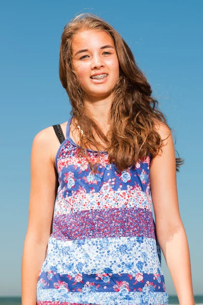 Glückliches hübsches Mädchen mit langen braunen Haaren, das an heißen Sommertagen den erfrischenden Strand genießt. blauer Himmel. — Stockfoto