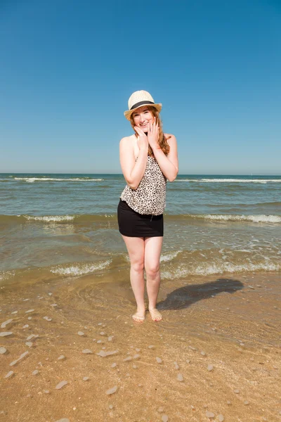 Menina bonita feliz com cabelo vermelho longo e chapéu desfrutando da praia refrescante no dia de verão quente. Céu azul claro . — Fotografia de Stock