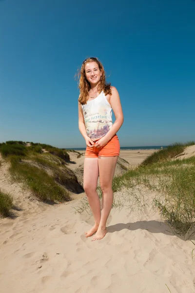 Gelukkig mooi meisje met lang rood haar zandduinen in de buurt van het strand genieten op hete zomers dag. duidelijke blauwe hemel. — Stockfoto