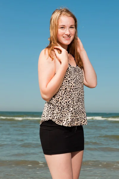 Ευτυχισμένο το όμορφο κορίτσι με μακριά κόκκινα μαλλιά, απολαμβάνοντας δροσιστικά παραλία την ημέρα καλοκαίρια. σαφή μπλε ουρανό. — Φωτογραφία Αρχείου