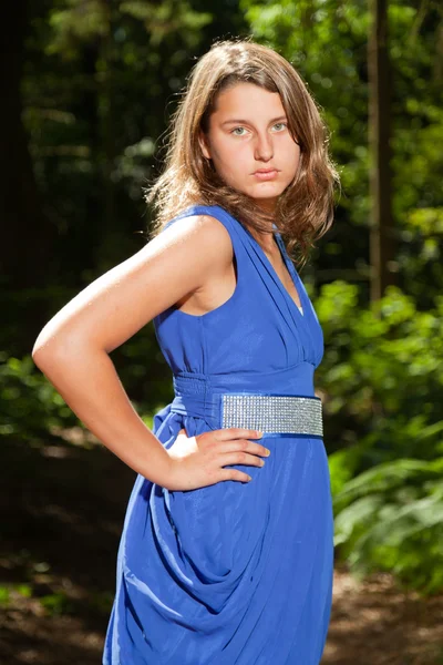 Csinos, fiatal nő, hosszú barna haja élvezi természet erdőben. zöld lomb háttér. kék ruhát visel. — Stock Fotó