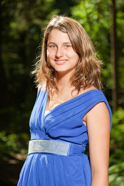 Αρκετά νεαρή γυναίκα με μακριά καστανά μαλλιά, απόλαυση της φύσης στο δάσος. φόντο πράσινο φύλλωμα. φορώντας μπλε φόρεμα. — Φωτογραφία Αρχείου