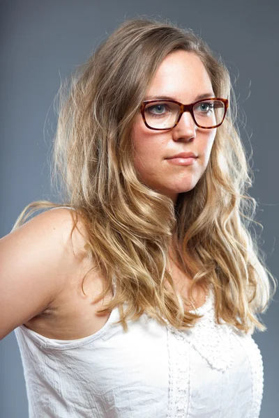 Mujer bonita con el pelo largo y castaño usando gafas. Estudio de moda filmado aislado sobre fondo gris . — Foto de Stock