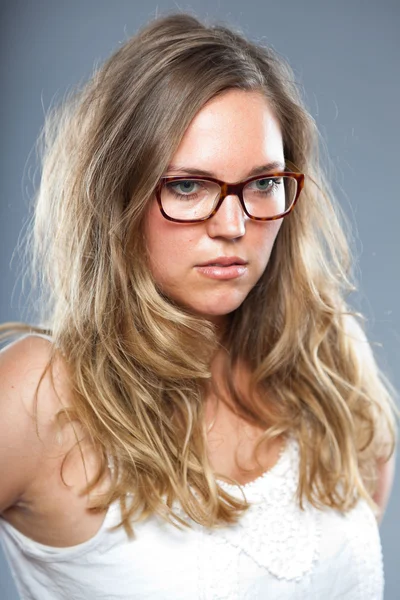Mujer bonita con el pelo largo y castaño usando gafas. Estudio de moda filmado aislado sobre fondo gris . — Foto de Stock