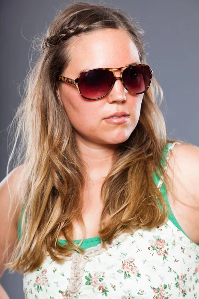 Mulher bonita com cabelo castanho longo usando óculos de sol e vestido de flor. Estúdio de moda tiro isolado em fundo cinza . — Fotografia de Stock
