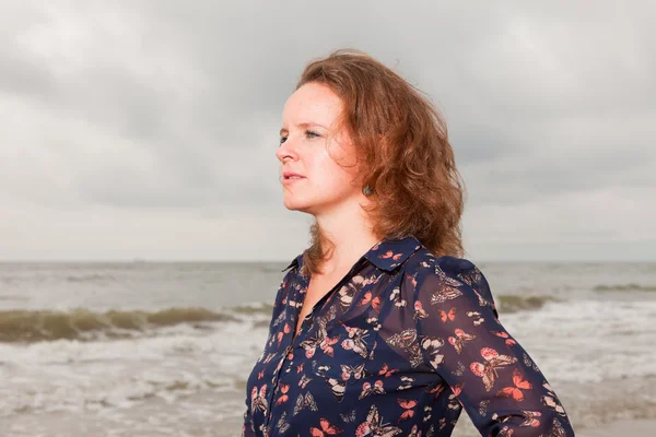 Αρκετά νεαρή γυναίκα που απολαμβάνουν υπαίθριο φύση, κοντά στην παραλία. κόκκινα μαλλιά. φοράει σκούρο μπλε φόρεμα. συννεφιά. — Φωτογραφία Αρχείου