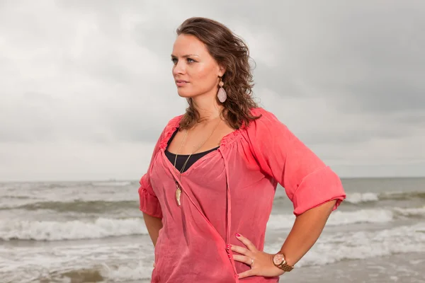 Hübsche junge Frau, die die Natur in Strandnähe genießt. braune Haare. trägt rosa Hemd. Bewölkter Himmel. — Stockfoto
