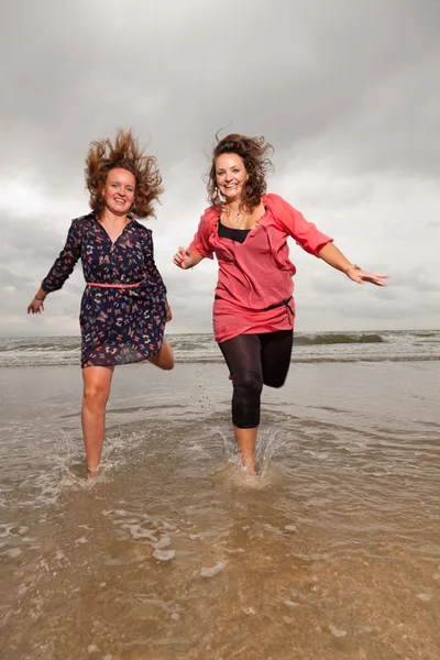 Two happy girls enjoying outdoor nature near the beach. Red and brown hair. Cloudy sky. — Stock Photo, Image