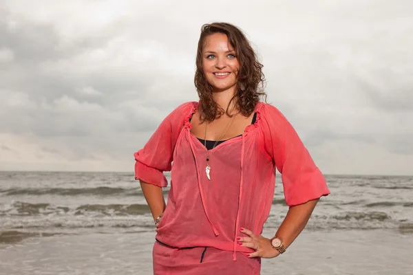 Mujer joven y feliz disfrutando de la naturaleza al aire libre cerca de la playa. Cabello castaño. Llevando camisa rosa. Cielo nublado . —  Fotos de Stock