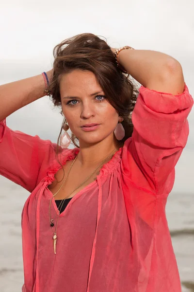 Glückliche junge Frau, die die Natur in Strandnähe genießt. braune Haare. trägt rosa Hemd. Bewölkter Himmel. — Stockfoto