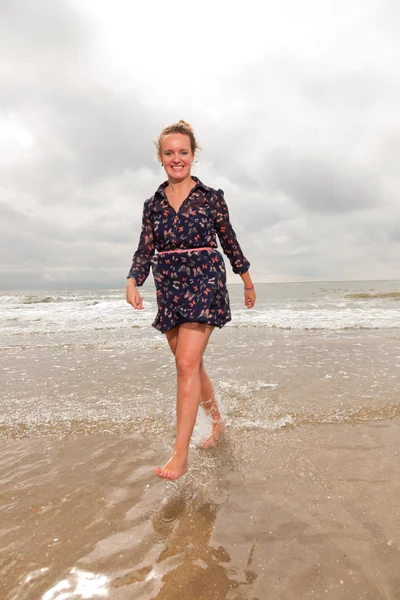 Mulher muito jovem desfrutando de natureza ao ar livre perto da praia. Andar na água. Cabelo vermelho. Vestido de azul escuro. Céu nublado . — Fotografia de Stock
