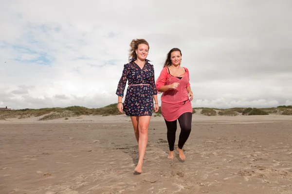 Дві щасливі дівчата насолоджуються природою на свіжому повітрі біля пляжу. Червоне і коричневе волосся. Хмарне небо . — стокове фото