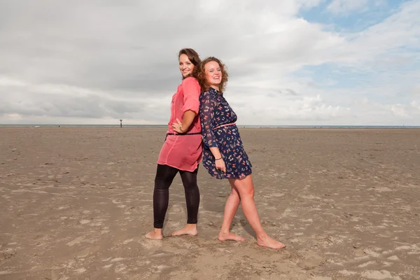 Две счастливые девушки наслаждаются природой возле пляжа. Рыжие и каштановые волосы. Облачное небо . — стоковое фото