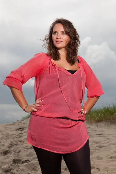 Happy young woman enjoying outdoor nature near the beach. Brown hair. Wearing pink shirt. Cloudy sky. — Stock Photo, Image
