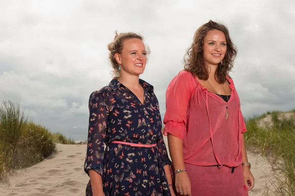 Zwei glückliche Mädchen, die die Natur in Strandnähe genießen. rote und braune Haare. Bewölkter Himmel. — Stockfoto