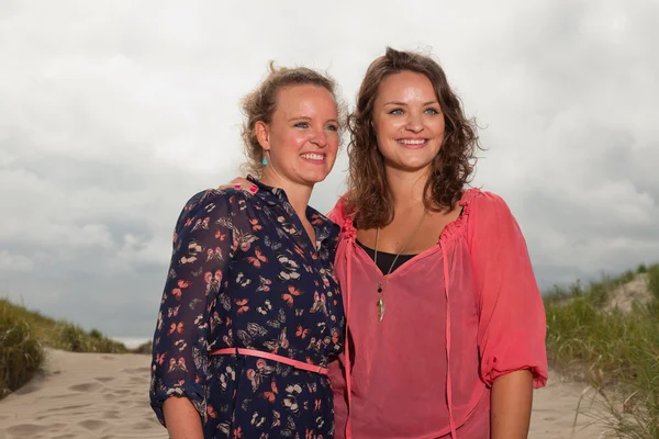 Två glada tjejer njuta utomhus natur nära stranden. röda och bruna hår. molnig himmel. — Stockfoto
