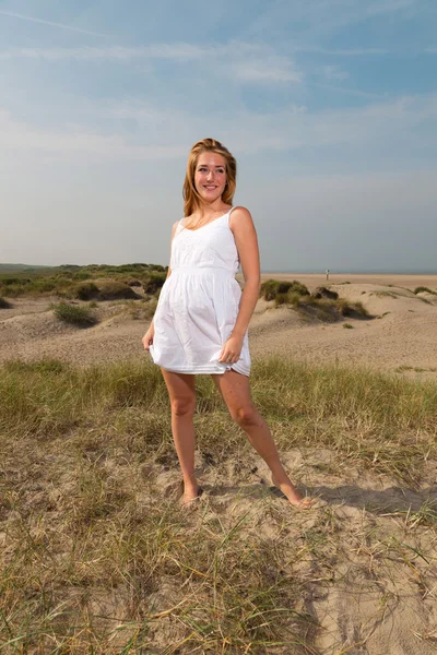Красива дівчина з рудим довгим волоссям в білій сукні насолоджується природою біля пляжу. Гарячий літній день з блакитним хмарним небом . — стокове фото