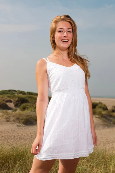 Menina bonita com cabelo longo vermelho vestindo vestido branco apreciando a natureza perto da praia. Dia quente de verão com céu azul nublado . — Fotografia de Stock