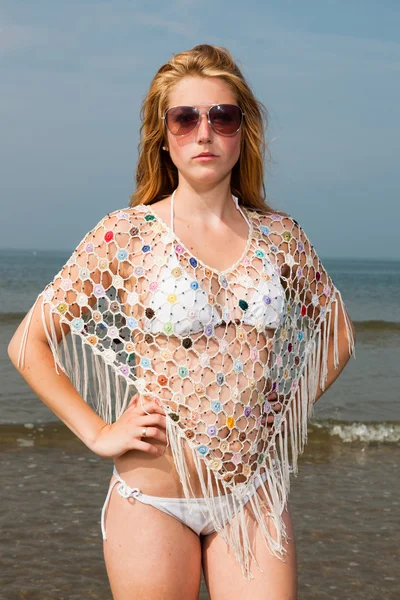 Csinos lány visel fehér bikini és a tengerparton szabadtéri élvezi napszemüveg, vörös hosszú haj. forró nyári napon a kék felhős ég. — Stock Fotó