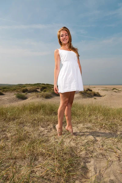 Menina bonita com cabelo longo vermelho vestindo vestido branco apreciando a natureza perto da praia. Dia quente de verão com céu azul nublado . — Fotografia de Stock