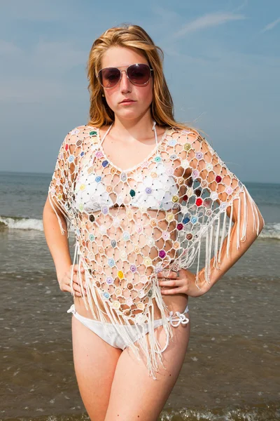 Красивая девушка с рыжими длинными волосами в белом бикини и солнечных очках, наслаждающаяся на открытом воздухе на пляже. Жаркий летний день с голубым облачным небом . — стоковое фото