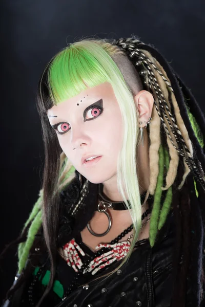 Chica cyber punk con cabello rubio verde y ojos rojos aislados sobre fondo negro con humo. Cara expresiva. Captura de estudio . — Foto de Stock