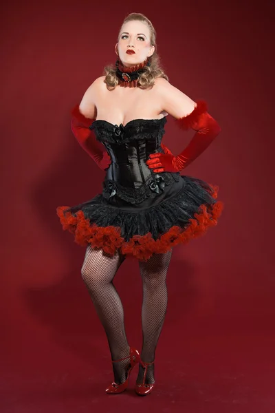 Seksi burlesque pin up uzun sarı saçlı kadın siyah ve kırmızı giymiş. studio moda üzerinde izole kırmızı arka plan vurdu. — Stok fotoğraf