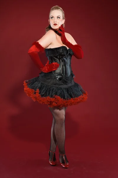 Σέξι παρωδίακο καρφίτσα μέχρι γυναίκα με μακριά ξανθά μαλλιά, ντυμένος με μαύρο και κόκκινο. στούντιο μόδας πυροβόλησε απομονωμένες σε κόκκινο φόντο. — Φωτογραφία Αρχείου