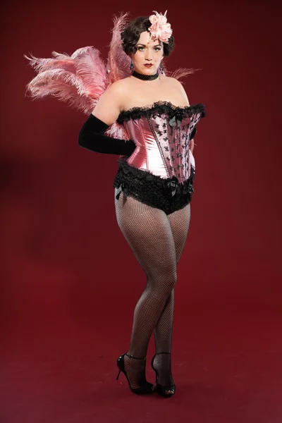 Сексуальная женщина в бурлеске с длинными светлыми волосами, одетая в розовое и черное. Студийный кадр на красном фоне . — стоковое фото